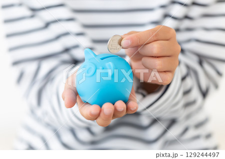 ブルーの豚の貯金箱にお金を入れる小学生の男の子 ブルーの豚の貯金箱にお金を入れる小学生の男の子 129244497