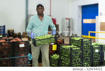 Loader stacks crates of beans in factory warehouse 129244521