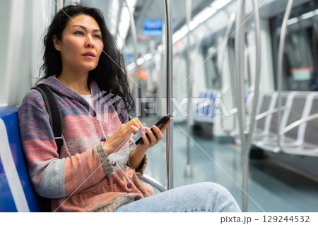 Woman passenger using phone in subway car 129244532