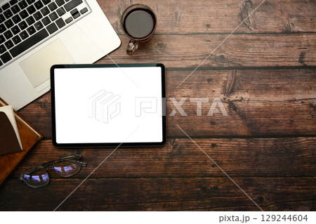 Top view of digital tablet with blank white screen on rustic wooden desk 129244604