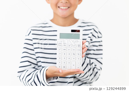 電卓を持って微笑む小学生の男の子 129244899