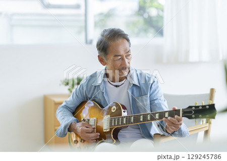 エレキギターを弾く60代の男性 129245786