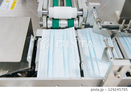Face mask, Surgical mask production line, Closeup machine conveyor belt roller in hygiene factory 129245795