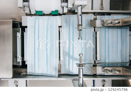 Face mask, Surgical mask production line, Closeup machine conveyor belt roller in hygiene factory 129245796