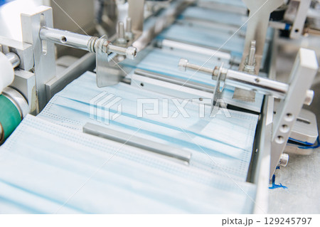 Face mask, Surgical mask production line, Closeup machine conveyor belt roller in hygiene factory 129245797