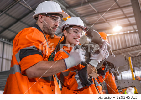 Robotic technician engineer male training helping young women team control operate robot welding arm Robotic technician engineer male training helping young women team control operate robot welding arm 129245813
