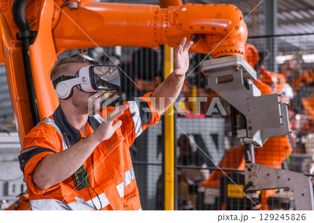 Engineer male using VR headset device to control operate robot arm in modern technology industry Engineer male using VR headset device to control operate robot arm in modern technology industry 129245826