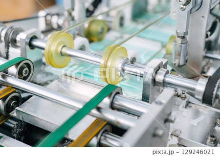 Face mask, Surgical mask production line, Closeup machine conveyor belt roller in hygiene factory 129246021