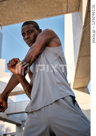 Man stretching in activewear during outdoor workout in urban environment Man stretching in activewear during outdoor workout in urban environment 129246116