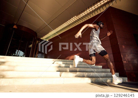 Athletic man sprinting up stairs with determination and energy outdoors 129246145