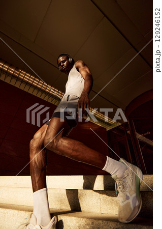 Athletic man in workout gear ascending stairs during an outdoor training session 129246152