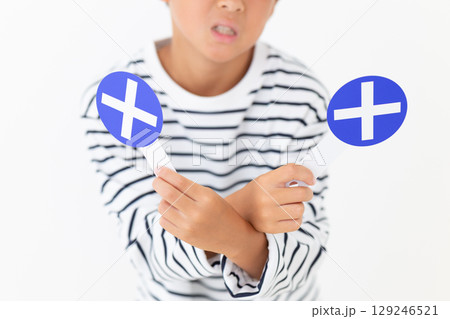 バツのプレートを持って笑う小学生の男の子 129246521