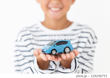 自動車の模型を持って微笑む小学生の男の子 129246755
