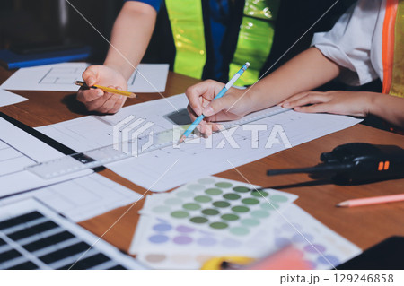 Closeup of team of industrial engineers meeting analyze machinery blueprints consult project on table in manufacturing factory. Working in manufacturing plant or production plant. 129246858