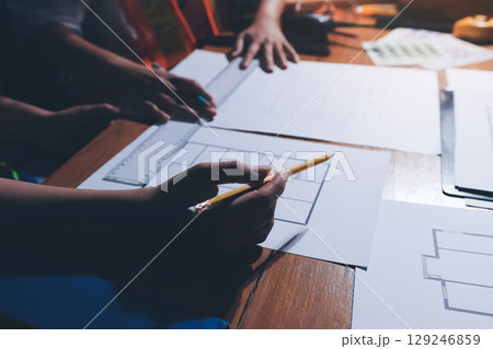 Closeup of team of industrial engineers meeting analyze machinery blueprints consult project on table in manufacturing factory. Working in manufacturing plant or production plant. 129246859