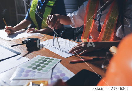 Closeup of team of industrial engineers meeting analyze machinery blueprints consult project on table in manufacturing factory. Working in manufacturing plant or production plant. 129246861