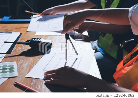 Closeup of team of industrial engineers meeting analyze machinery blueprints consult project on table in manufacturing factory. Working in manufacturing plant or production plant. 129246862
