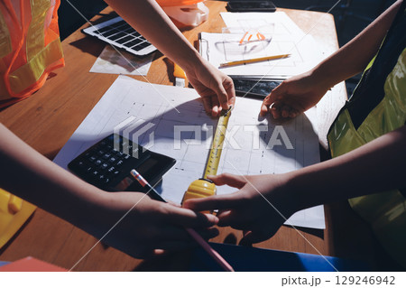 Closeup of team of industrial engineers meeting analyze machinery blueprints consult project on table in manufacturing factory. Working in manufacturing plant or production plant. Closeup of team of industrial engineers meeting analyze machinery blueprints consult project on table in manufacturing factory. Working in manufacturing plant or production plant. 129246942