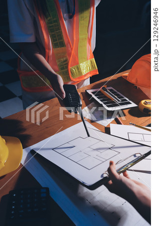 Closeup of team of industrial engineers meeting analyze machinery blueprints consult project on table in manufacturing factory. Working in manufacturing plant or production plant. Closeup of team of industrial engineers meeting analyze machinery blueprints consult project on table in manufacturing factory. Working in manufacturing plant or production plant. 129246946