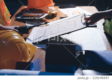 Closeup of team of industrial engineers meeting analyze machinery blueprints consult project on table in manufacturing factory. Working in manufacturing plant or production plant. Closeup of team of industrial engineers meeting analyze machinery blueprints consult project on table in manufacturing factory. Working in manufacturing plant or production plant. 129246947