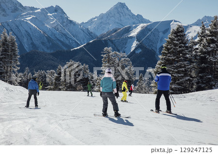 Snowboarders and skiers ski in the resort on the slopes 129247125