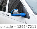 Broken side mirror of a white van temporarily fixed with blue tape, close-up on urban street background 129247211