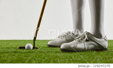 Close-up of golf shoes and putter on green grass 129247270