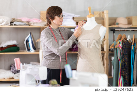 Seamstress shaping dress on mannequin in tailoring studio 129247622