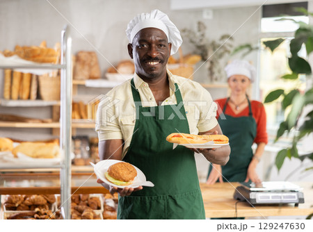 Smiling male baker with pastry in bakehouse 129247630