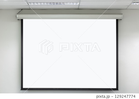 Front view of lecture room with empty white projector screen. 129247774