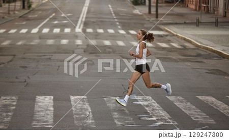 Female jogger running along city road for morning exercise Female jogger running along city road for morning exercise 129247800