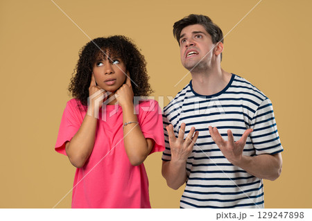 Grumpy man scolds on african american woman. Irritated girlfriend covered ears Grumpy man scolds on african american woman. Irritated girlfriend covered ears 129247898