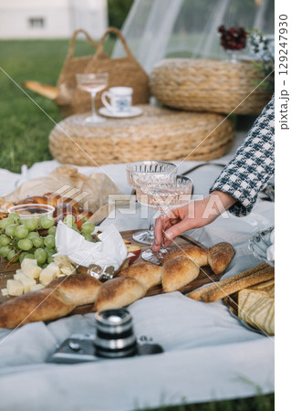 Elegant picnic setup with delicious food and drinks on a sunny day in a grassy area Elegant picnic setup with delicious food and drinks on a sunny day in a grassy area 129247930