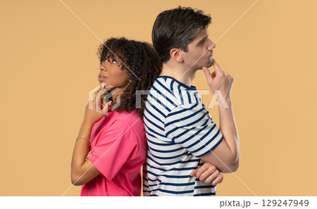 Young Black woman gazes dreamily, white male partner looks thoughtful, focused. 129247949