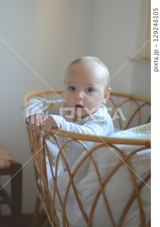Curious Baby Standing in Crib with Wide-Eyed Wonder 129248105