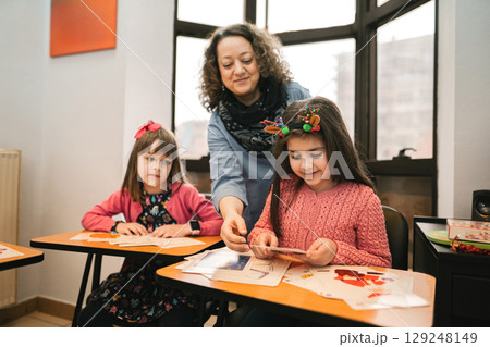 Female teacher helping elementary students at language school class Female teacher helping elementary students at language school class 129248149