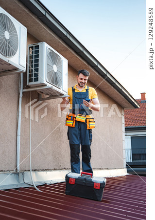Technician checking air conditioning outdoor unit on the roof 129248589
