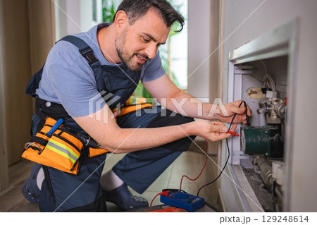 Electrician measuring voltage of heating pump in boiler room Electrician measuring voltage of heating pump in boiler room 129248614