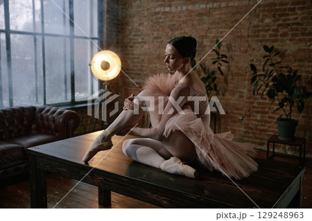 An elegant ballerina is posing gracefully on a table in a beautiful artistic setting An elegant ballerina is posing gracefully on a table in a beautiful artistic setting 129248963