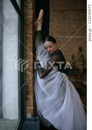 Elegant ballerina stretching gracefully in a beautiful and artistic studio setting Elegant ballerina stretching gracefully in a beautiful and artistic studio setting 129248972