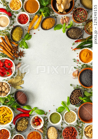 A lively frame of assorted herbs and spices on gray, highlighting the vibrant colors and flavors for cooking inspiration, top view and copy space 129249155