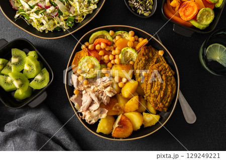 Enjoy a nutritious breakfast with baked sweet potato, carrots, zucchini, chicken breast, and lentil cutlets, complemented by a fresh salad and kiwi for dessert 129249221