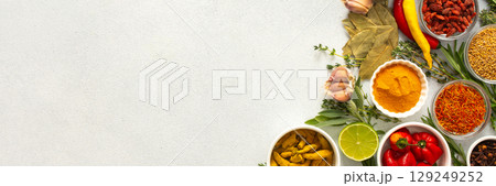 A mix of dried herbs and spices laid out on a gray background, highlighting natural flavors and culinary essentials, top view and copy space, banner 129249252