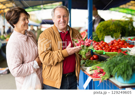 elderly man and woman buying radishes at an open market elderly man and woman buying radishes at an open market 129249605