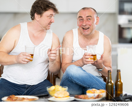 Two adult male friends drinking beer Two adult male friends drinking beer 129249606