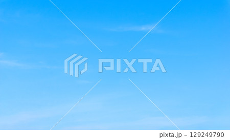シンプル青空の背景写真　夏の真っ青な快晴にかすかな雲　 129249790