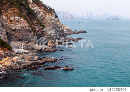 Coastal landscape with beautiful rocky cliffs extend into a calm blue sea Coastal landscape with beautiful rocky cliffs extend into a calm blue sea 129250491