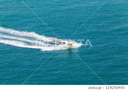 Large Fishing Boat Navigating Through Blue Ocean Waters at High Speed Large Fishing Boat Navigating Through Blue Ocean Waters at High Speed 129250493