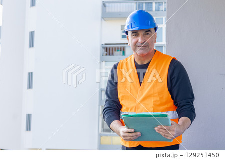 Front view portrait of a smiling civil engineer or factory worker wearing a blue helmet and looking at camera Front view portrait of a smiling civil engineer or factory worker wearing a blue helmet and looking at camera 129251450
