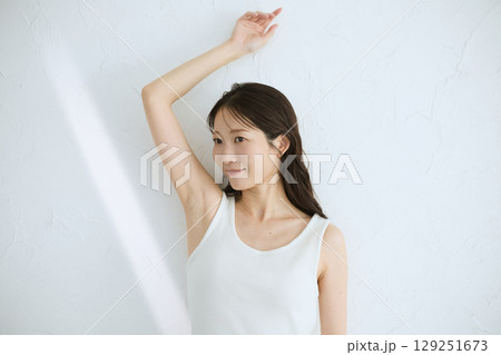 肌に触れてスキンケアする若い女性の笑顔 – 自然光・白背景 129251673